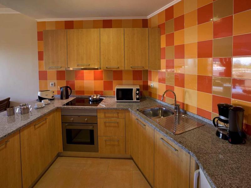 Moderne keuken met kleurrijke oranje-rode tegels en houten kasten.