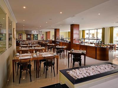 Helles Hotelrestaurant mit Holztischen und großen Fenstern für viel Tageslicht.