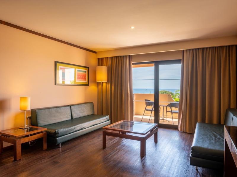 Modern eingerichtetes Hotelzimmer mit Blick auf Terrasse und Meer.