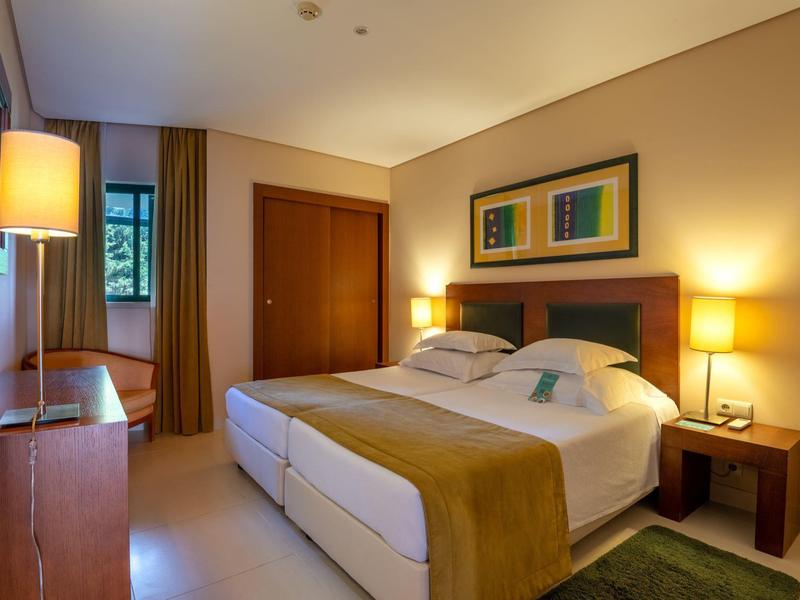 Gemütliches Hotelzimmer mit großem Bett, Nachttischen und warmem Licht.