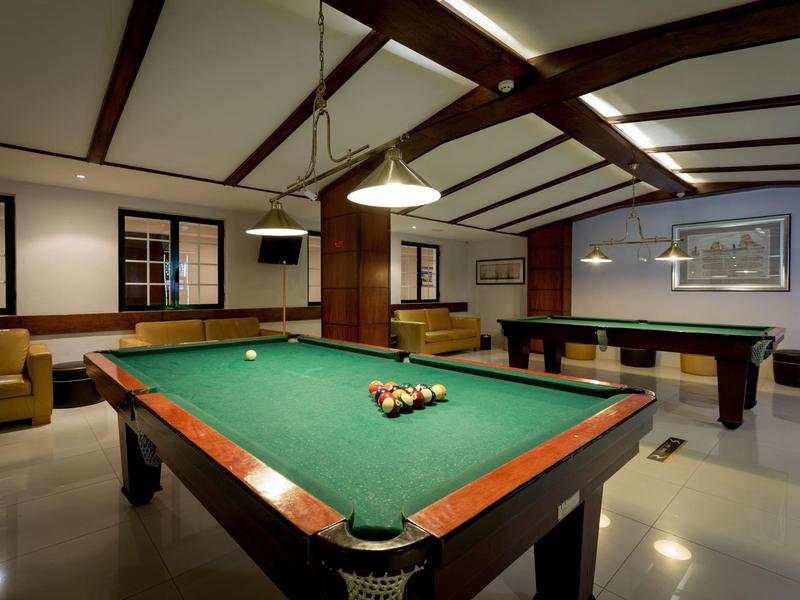 Innenraum mit Billardtisch, Sofa, großem Fenster, Deckenbalken und moderner Beleuchtung.