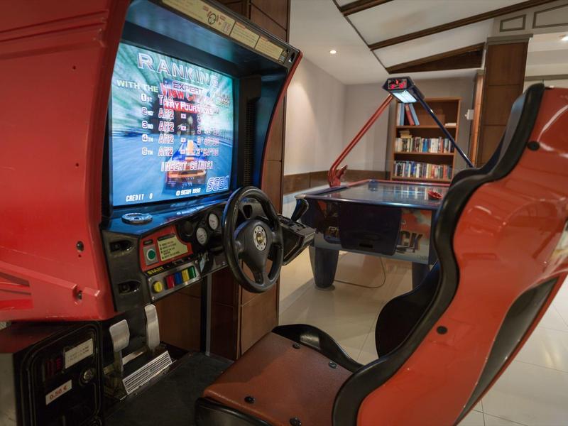 Ein rotes Rennspiel-Arcade mit Lenkrad und Sitz, daneben ein kleiner Air-Hockey-Tisch im Raum.