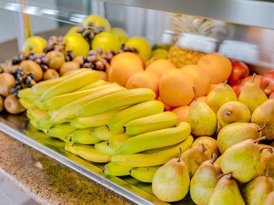 Toonbank met vers fruit zoals bananen, appels, peren en sinaasappels in een hotel.