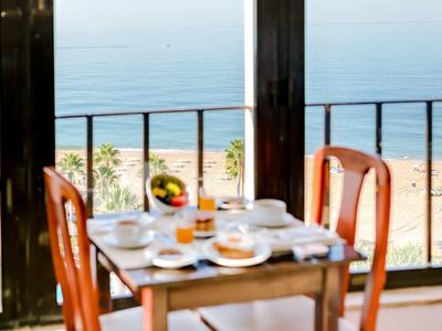 Een gedekte ontbijttafel met uitzicht op het strand door een glazen wand.