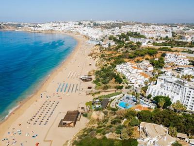 Luchtfoto van een zonnig strand met hotels en ligbedden langs de kust.
