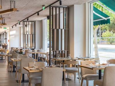 Světla, moderní restaurace s velkými okny a elegantně prostřenými stoly.