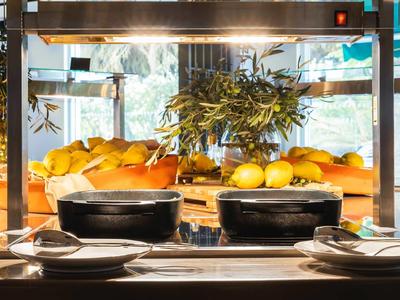 Čerstvé ovoce a pečivo na bufetovém pultu v jasné restauraci s přirozeným světlem.