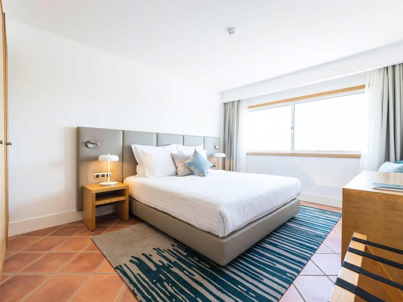 Luxusní venkovní posezení s baldachýnovou postelí, polštáři a dřevěnými židlemi na terase.