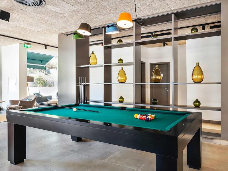 Moderní společenská místnost s kulečníkovým stolem a dekorativními zlatými vázy v hotelu.