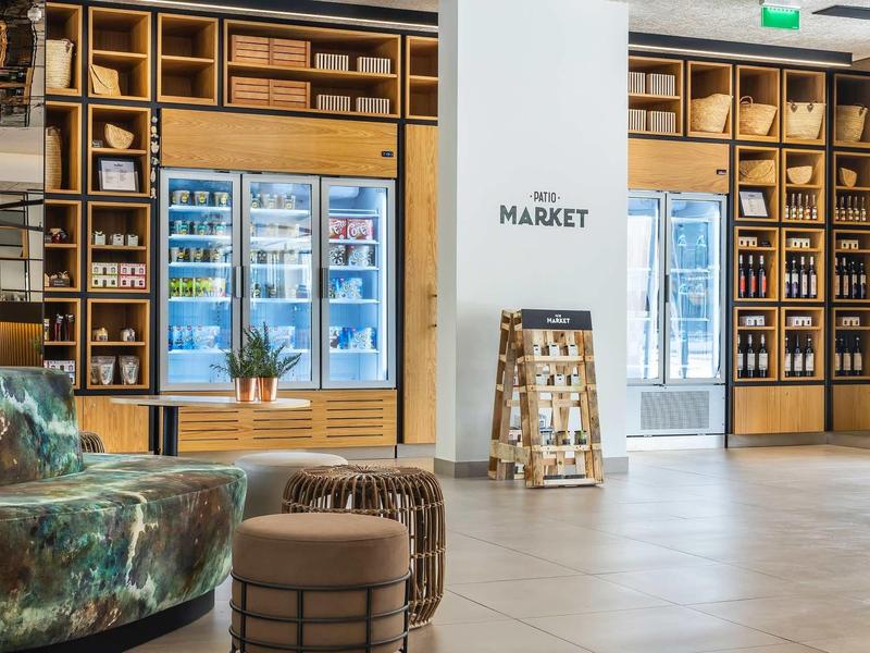 Moderní tržní prostor s dřevěnými regály, lednicemi a sezením v světlém prostoru.