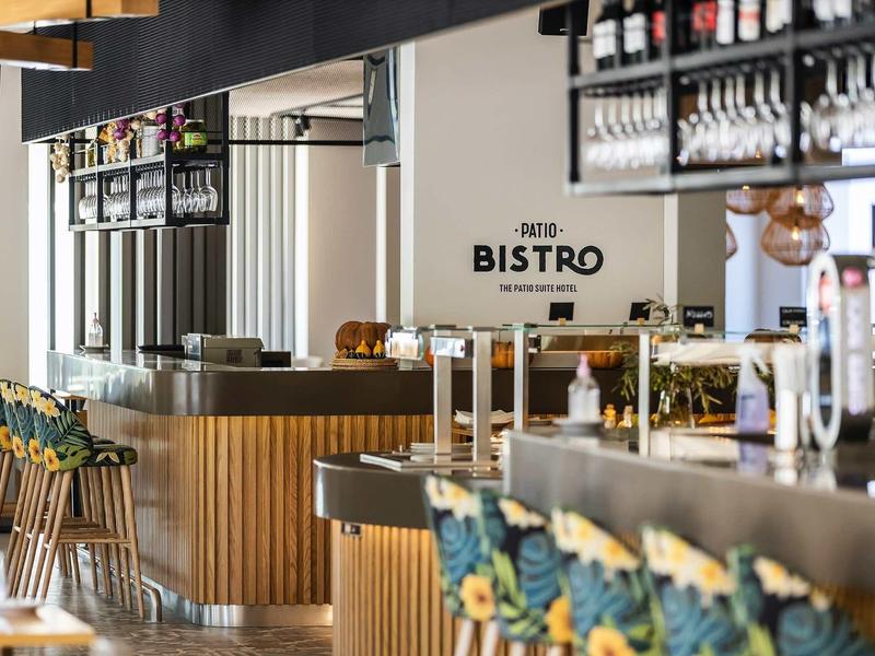 Moderní bistro s barevnými židlemi a dřevěným pultem.