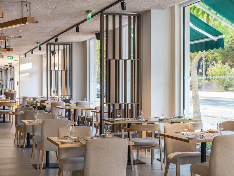 Světla, moderní restaurace s velkými okny a elegantně prostřenými stoly.