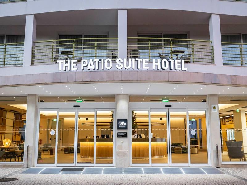 Osvětlený vstup do The Patio Suite Hotel s moderním a vstřícným designem.