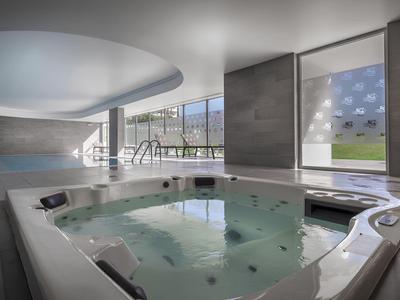 Jacuzzi interior moderno con ventana grande y luz natural en un spa de hotel.