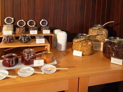 Mesa con frascos de mermeladas y cereales en un buffet de desayuno de hotel.