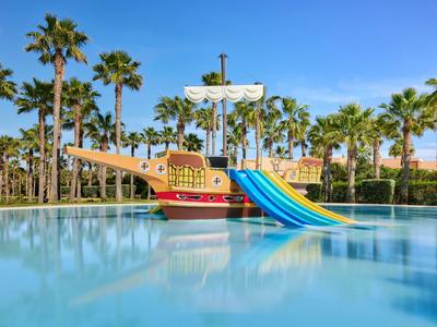 Aire de jeux pour enfants en forme de bateau pirate avec toboggans bleus dans la piscine près des palmiers