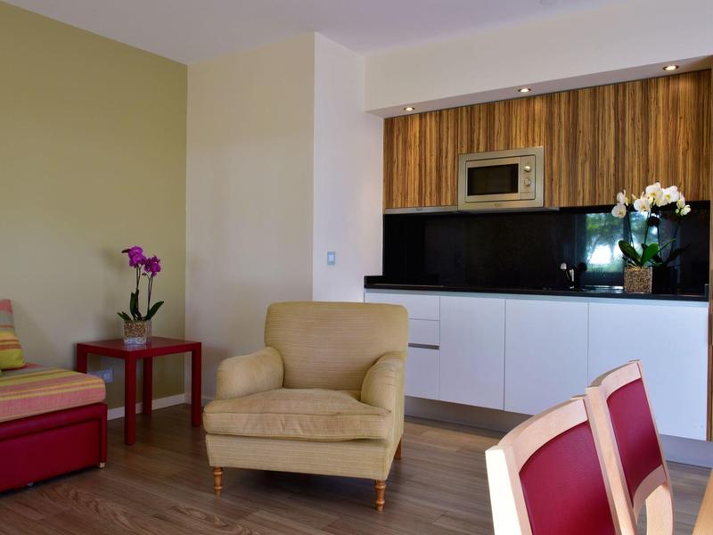 Gemütliches Wohnzimmer mit bequemen Sesseln und moderner Küchenzeile im Hintergrund.