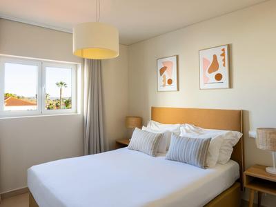 Helles Schlafzimmer mit großen Fenstern, Doppelbett und moderner Dekoration.