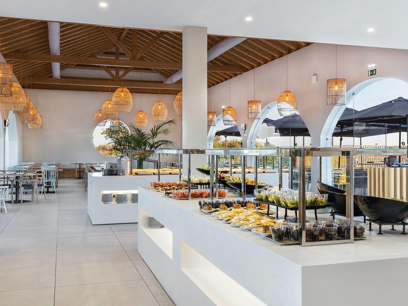 Heller Buffetbereich mit weißen Möbeln, Holzelementen und vielfältigem Essen auf mehreren Buffets.