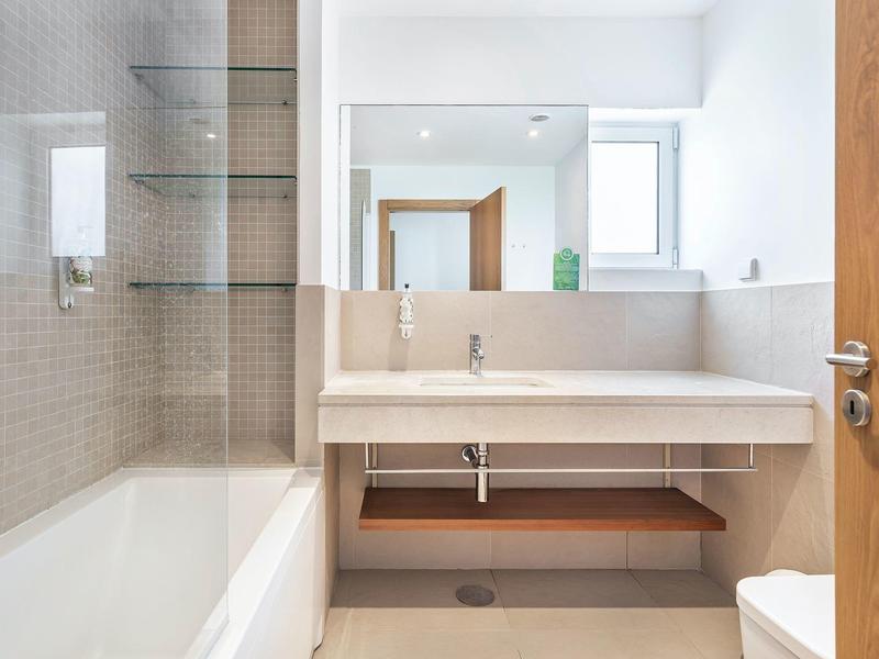 Moderner heller Badraum mit Badewanne, großer Spiegel und offenem Regal unter dem Waschbecken.