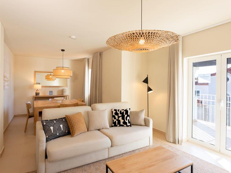 Modern eingerichtetes Wohnzimmer mit Sofa, Couchtisch und Zugang zu Balkon.