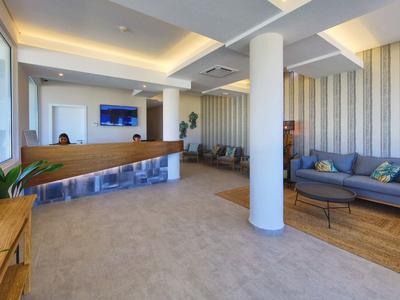 Moderne Hotellobby mit Empfangstresen, Sofas, hellen Wänden und indirekter Deckenbeleuchtung.