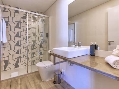 Modernes Badezimmer mit Dusche, weißem Waschbecken, großem Spiegel und Holzboden.