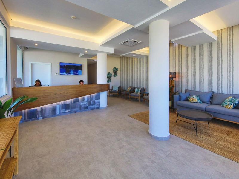 Moderne Hotellobby mit Empfangstresen, Sofas, hellen Wänden und indirekter Deckenbeleuchtung.