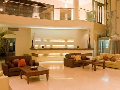 Heller Hotel-Lobbybereich mit modernen Sofas, Tischen und Empfangstresen.