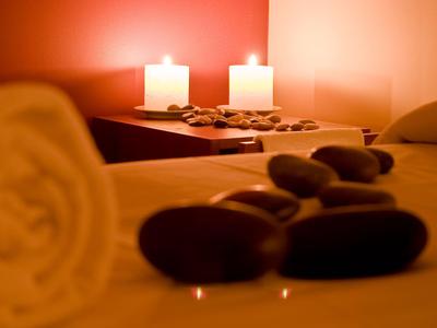 Sanfte Beleuchtung mit Kerzen und warmer Atmosphäre auf Massagebett mit Steinen.