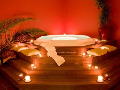Entspannendes Spa-Setting mit Whirlpool, Kerzenlicht und Kissen auf Holzboden.