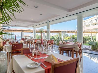 Hell beleuchtetes Restaurant mit gedeckten Tischen und Blick auf die Außenterrasse.