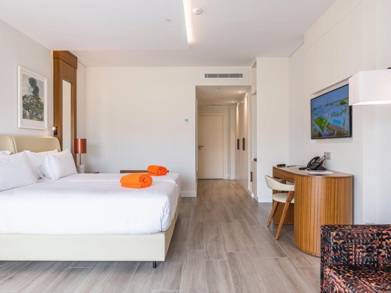 Helles, modernes Hotelzimmer mit Doppelbett, Holzfußboden, Schreibtisch und Wand-TV.