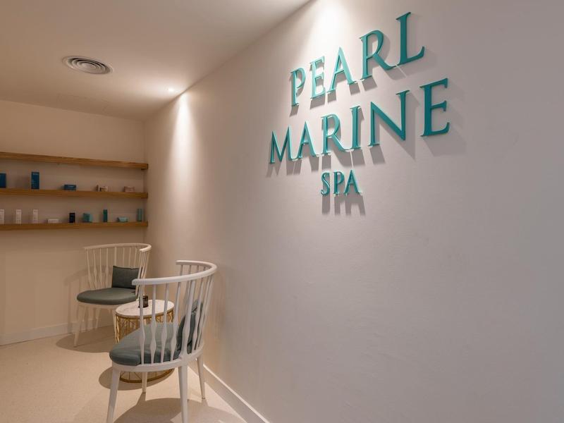 Helle, minimalistische Spa-Ecke mit weißem Sessel, kleinem Tisch und "PEARL MARINE SPA" Schriftzug.