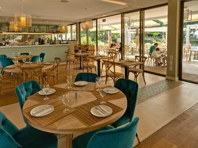 Moderner Hotelrestaurantinnenraum mit Holzböden, blauen Stühlen und Tischgedecken.