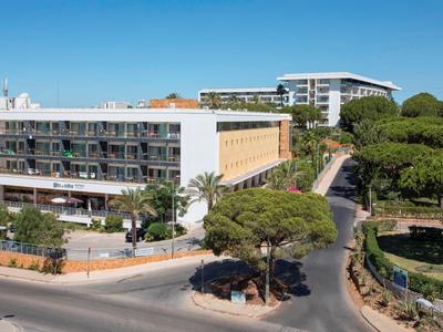 Modernes Hotel mit weißen Fassaden und umliegenden Straßen unter klarem blauem Himmel.