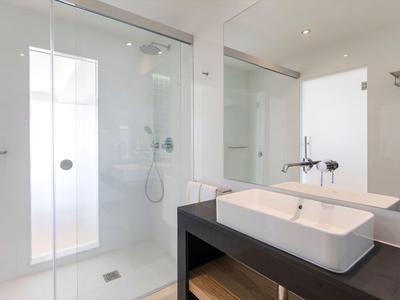 Modernes Hotelbadezimmer mit Glasdusche, weißem Waschbecken und großem Spiegel.