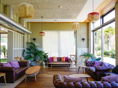 Helles Wohnzimmer mit bequemen Sofas, großen Fenstern und tropischen Pflanzen.