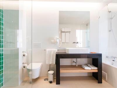 Modernes Badezimmer mit Dusche, Badewanne, Toilette und schwarzem Waschbeckenunterschrank.