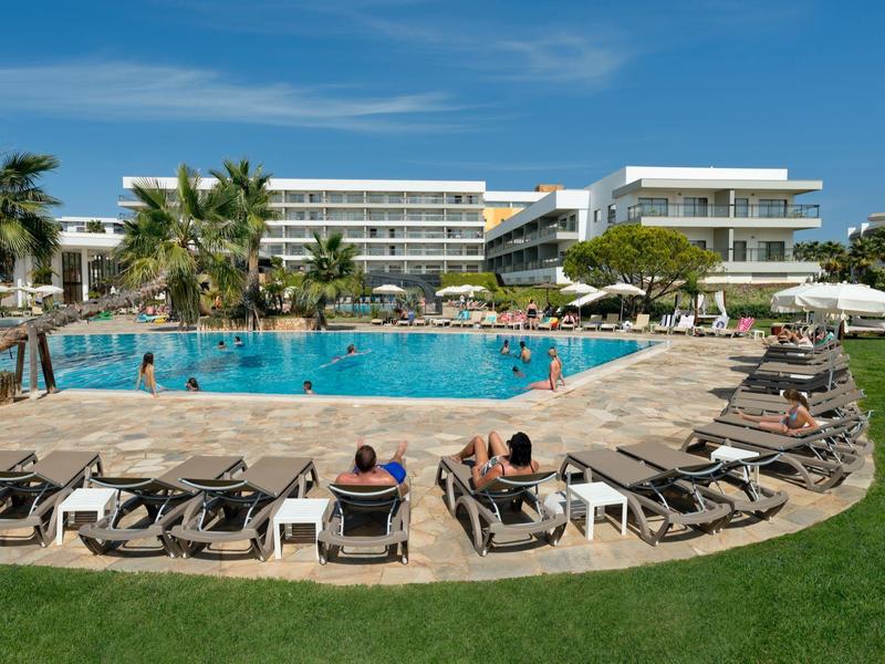 Moderner Hotelpool mit Liegestühlen, Palmen und Gästen an einem sonnigen Tag