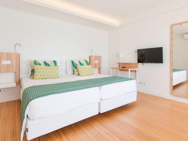 Modernes Hotelzimmer mit Doppelbett, Holzfußboden und großem Spiegel