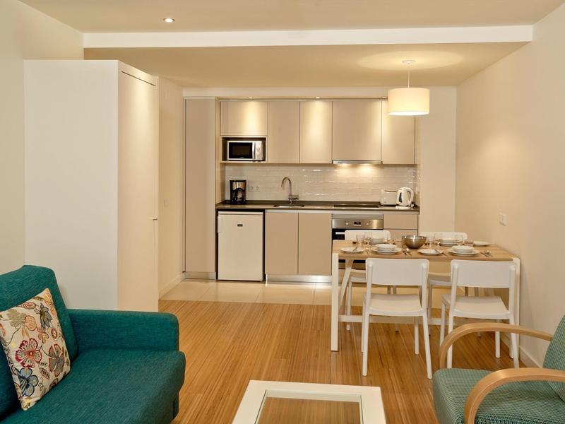 Modern eingerichtetes Apartment mit Küchenzeile, Esstisch und Sitzecke mit Sofas.