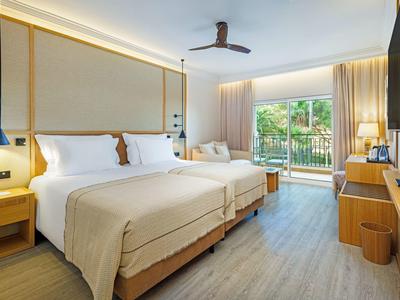 Modernes Hotelzimmer mit zwei Betten, Balkon und hellen Holzmöbeln.