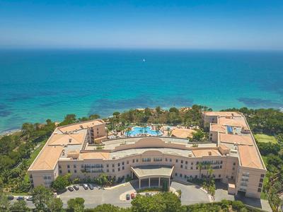 Helles Hotelzimmer mit zwei Betten und Terrasse mit Blick auf den Pool.