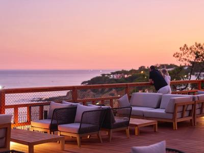 Hölzerne Dachterrasse mit gemütlichen Sofas und Meerblick bei Sonnenuntergang.