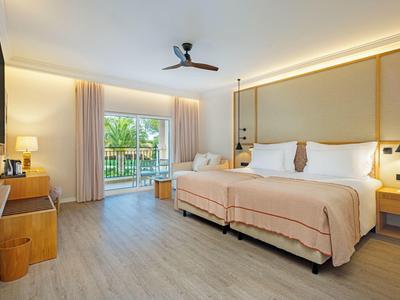 Modernes Hotelzimmer mit zwei Betten, Balkon und natürlichem Licht.