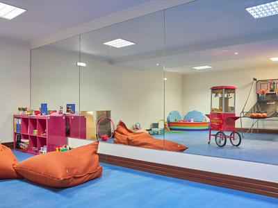 Kinderspielraum mit Kissen, Regalen und Popcornmaschine in hellem, sicherem Bereich.