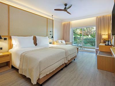 Helles Hotelzimmer mit zwei Betten, Terrassentür und modernem Dekor.