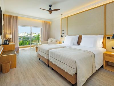 Helles Hotelzimmer mit zwei Einzelbetten, Balkon und modernem Interieur.