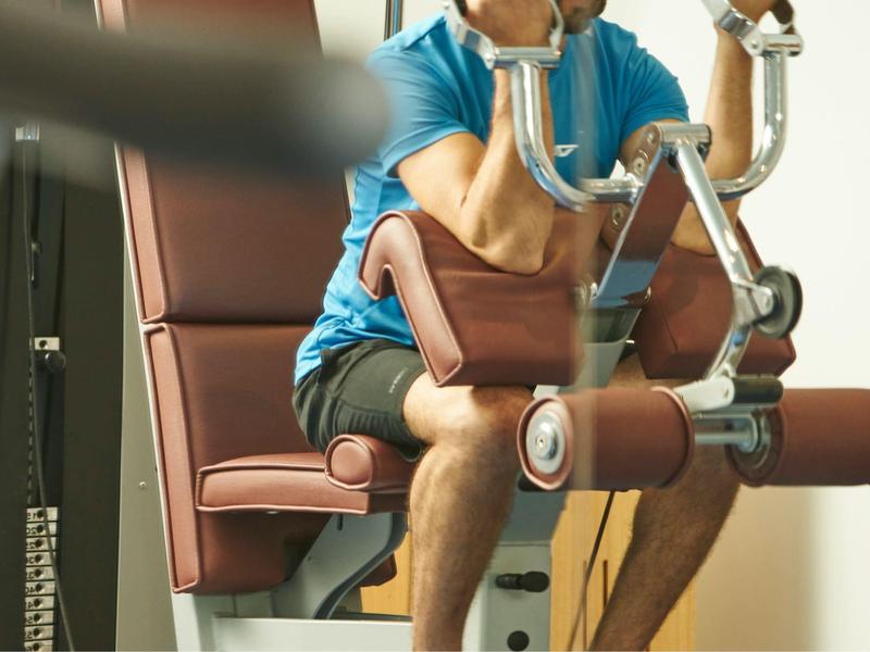 Mann trainiert Beine an Fitnessgerät in modernem Fitnessraum.